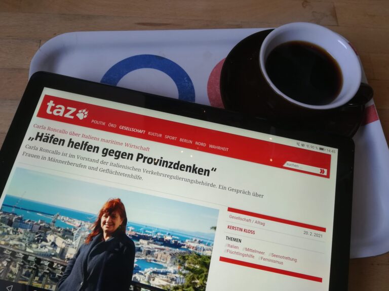 Tablet mit taz-Interview mit Carla Roncallo neben gefüllter Espresso-Tasse auf Tablett.