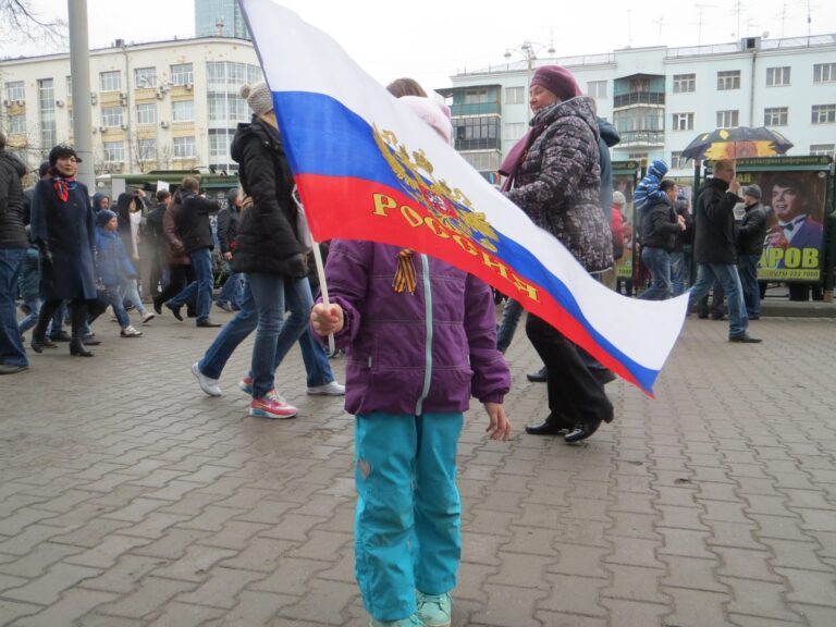 Kind auf einer belebten Straße in Jekaterinburg hält russische Flagge.