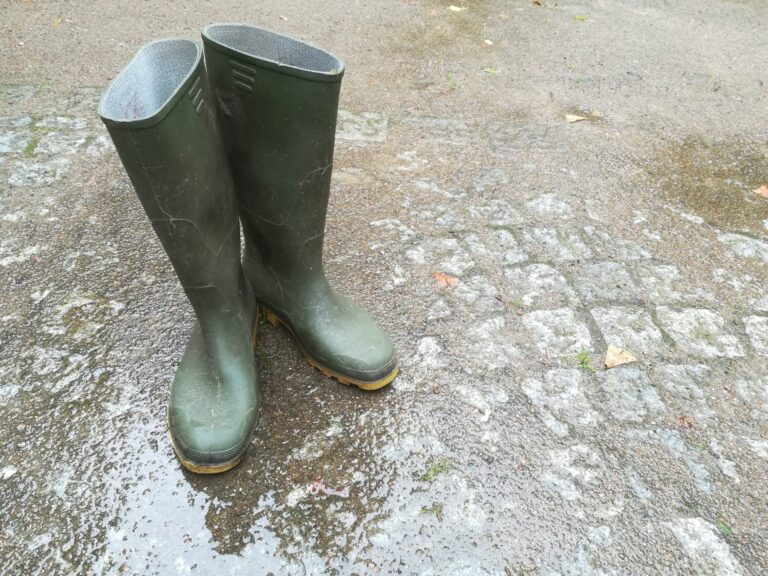 Olivgrüne Gummistiefel auf Matschboden